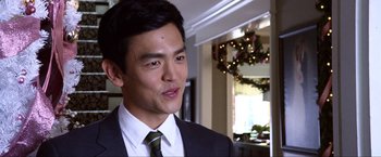 Movie still from “A Very Harold & Kumar Christmas” (2011), directed by Todd Strauss-Schulson – A man wearing a suit and tie standing in front of a window; Close Up shot, Over the shoulder angle