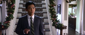 Movie still from “A Very Harold & Kumar Christmas” (2011), directed by Todd Strauss-Schulson – A man in a suit and tie holding a cell phone; Medium shot, Over the shoulder angle