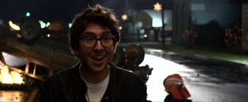 Movie still from “A Very Harold & Kumar Christmas” (2011), directed by Todd Strauss-Schulson – A man with glasses is smiling for the camera; Close Up shot, Over the shoulder angle