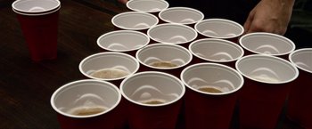 A group of red cups filled with brown liquid on top of a wooden table