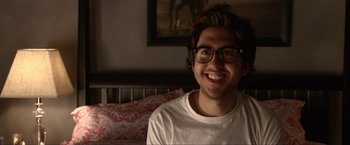 Movie still from “A Very Harold & Kumar Christmas” (2011), directed by Todd Strauss-Schulson – A young man with glasses smiling for the camera; Close Up shot, Over the shoulder angle