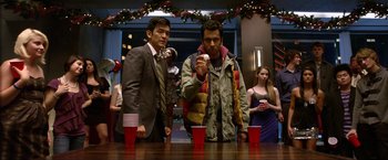Movie still from “A Very Harold & Kumar Christmas” (2011), directed by Todd Strauss-Schulson – Two men standing at a table with red solo cups; Medium shot, Over the shoulder angle
