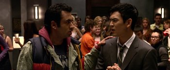Movie still from “A Very Harold & Kumar Christmas” (2011), directed by Todd Strauss-Schulson – Two men talking to each other in front of a group of people; Close Up shot, Over the shoulder angle