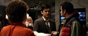 Movie still from “A Very Harold & Kumar Christmas” (2011), directed by Todd Strauss-Schulson – A group of people standing around a table; Medium shot, Over the shoulder angle