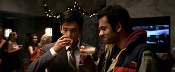 Movie still from “A Very Harold & Kumar Christmas” (2011), directed by Todd Strauss-Schulson – Two young men are enjoying a drink at a party; Close Up shot, Over the shoulder angle