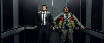 Movie still from “A Very Harold & Kumar Christmas” (2011), directed by Todd Strauss-Schulson – Two men standing next to each other in an elevator; Medium shot, Low angle
