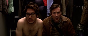 Movie still from “A Very Harold & Kumar Christmas” (2011), directed by Todd Strauss-Schulson – Two men sitting next to each other in front of a wall; Medium shot, Overhead angle