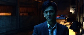 Movie still from “A Very Harold & Kumar Christmas” (2011), directed by Todd Strauss-Schulson – A man wearing a suit and tie standing in the dark; Close Up shot, Over the shoulder angle