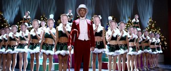 A man in a red suit standing in front of a group of girls