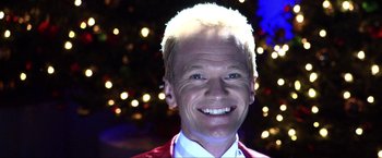 Movie still from “A Very Harold & Kumar Christmas” (2011), directed by Todd Strauss-Schulson – A person wearing a suit and smiling; Close Up shot, Low angle
