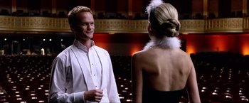 Movie still from “A Very Harold & Kumar Christmas” (2011), directed by Todd Strauss-Schulson – A man and a woman are standing in front of an audience; Medium shot, Over the shoulder angle