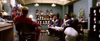 Movie still from “A Very Harold & Kumar Christmas” (2011), directed by Todd Strauss-Schulson – Two men sitting in chairs in a room with wigs on the wall; Wide shot, Over the shoulder angle