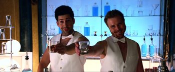 Movie still from “A Very Harold & Kumar Christmas” (2011), directed by Todd Strauss-Schulson – A couple of men holding a glass of water in a room; Medium shot, Low angle