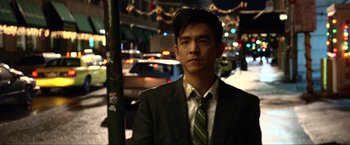 Movie still from “A Very Harold & Kumar Christmas” (2011), directed by Todd Strauss-Schulson – A man wearing a suit and tie standing on a sidewalk; Close Up shot, Over the shoulder angle
