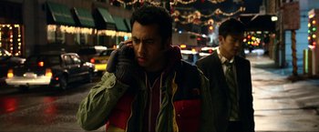 Movie still from “A Very Harold & Kumar Christmas” (2011), directed by Todd Strauss-Schulson – A man in a winter coat is talking on a cell phone; Medium shot, Over the shoulder angle