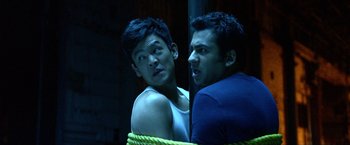 Movie still from “A Very Harold & Kumar Christmas” (2011), directed by Todd Strauss-Schulson – Two young men standing next to each other in a room; Medium shot, Low angle