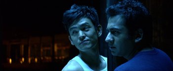 Movie still from “A Very Harold & Kumar Christmas” (2011), directed by Todd Strauss-Schulson – A man standing next to another man in a dark room; Close Up shot, Over the shoulder angle