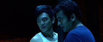 Movie still from “A Very Harold & Kumar Christmas” (2011), directed by Todd Strauss-Schulson – Two young asian men standing next to each other in a dark room; Close Up shot, Over the shoulder angle