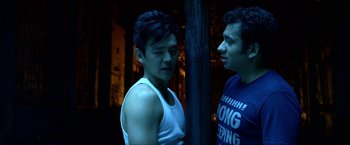 Movie still from “A Very Harold & Kumar Christmas” (2011), directed by Todd Strauss-Schulson – Two young men standing next to each other in a dark room; Medium shot, Over the shoulder angle