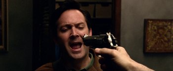 Movie still from “A Very Harold & Kumar Christmas” (2011), directed by Todd Strauss-Schulson – A man is holding a gun up to his mouth; Close Up shot, Overhead angle