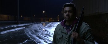 Movie still from “A Very Harold & Kumar Christmas” (2011), directed by Todd Strauss-Schulson – A man standing in the rain holding a walking stick; Close Up shot, Over the shoulder angle