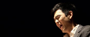 A young man is singing in front of a black background