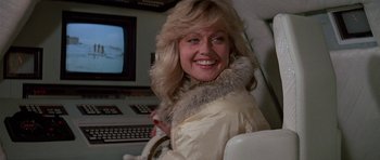 Movie still from “A View to a Kill” (1985), directed by John Glen – A woman with blonde hair wearing a white jacket; Close Up shot, Over the shoulder angle