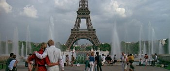 Movie still from “A View to a Kill” (1985), directed by John Glen – A group of people standing in front of the eiffel tower; Extreme Wide shot, Over the shoulder angle