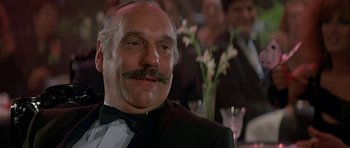Movie still from “A View to a Kill” (1985), directed by John Glen – An older man with a mustache and a bow tie; Close Up shot, Low angle