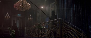 Movie still from “A View to a Kill” (1985), directed by John Glen – A man standing on a balcony next to a chandelier; Wide shot, Low angle