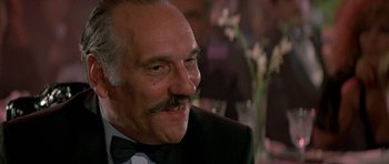 Movie still from “A View to a Kill” (1985), directed by John Glen – An older man wearing a black suit and a bow tie; Close Up shot, Low angle