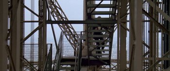 Movie still from “A View to a Kill” (1985), directed by John Glen – Two people are walking up a set of stairs on a bridge; Extreme Wide shot, Low angle