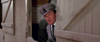 Movie still from “A View to a Kill” (1985), directed by John Glen – A man wearing a hat and a tie; Close Up shot, Low angle