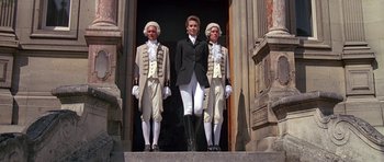 Movie still from “A View to a Kill” (1985), directed by John Glen – A group of men standing next to each other on steps; Wide shot, Low angle