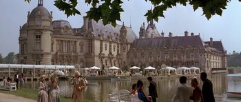 Movie still from “A View to a Kill” (1985), directed by John Glen – A group of people sitting on a bench near a body of water; Extreme Wide shot, High angle