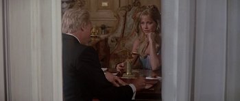 Movie still from “A View to a Kill” (1985), directed by John Glen – A man and a woman sitting at a dinner table; Medium shot, Over the shoulder angle