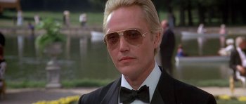 Movie still from “A View to a Kill” (1985), directed by John Glen – A person wearing a suit and sunglasses; Close Up shot, Low angle