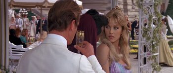Movie still from “A View to a Kill” (1985), directed by John Glen – A man holding a wine glass in front of a beautiful woman; Close Up shot, Over the shoulder angle