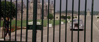 Movie still from “A View to a Kill” (1985), directed by John Glen – A view through a gate of a large building; Extreme Wide shot, High angle