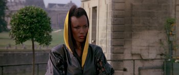 Movie still from “A View to a Kill” (1985), directed by John Glen – A woman in a leather jacket with a yellow scarf around her neck; Close Up shot, Low angle