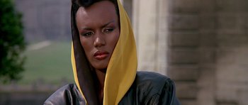 Movie still from “A View to a Kill” (1985), directed by John Glen – A woman with a yellow scarf on her head; Close Up shot, Low angle