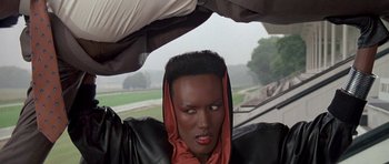 Movie still from “A View to a Kill” (1985), directed by John Glen – A woman with a red head scarf and a black jacket; Close Up shot, Low angle