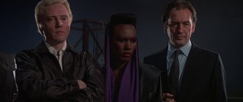 Movie still from “A View to a Kill” (1985), directed by John Glen – A group of people standing next to each other; Medium shot, Low angle