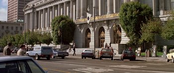 Movie still from “A View to a Kill” (1985), directed by John Glen – A group of people walking down a street near a building; Extreme Wide shot, High angle