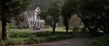 Movie still from “A View to a Kill” (1985), directed by John Glen – A car driving down a street near a house; Extreme Wide shot, Low angle