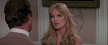 Movie still from “A View to a Kill” (1985), directed by John Glen – A woman with long blonde hair and blue eye shadow; Close Up shot, Over the shoulder angle