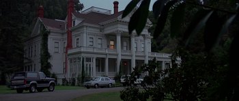 Movie still from “A View to a Kill” (1985), directed by John Glen – An old white house with cars parked in front of it; Wide shot, Low angle
