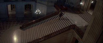 Movie still from “A View to a Kill” (1985), directed by John Glen – A man and woman walking up a staircase; Extreme Wide shot, High angle