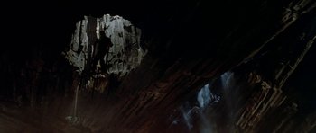 Movie still from “A View to a Kill” (1985), directed by John Glen – A man is climbing up the side of a cave; Extreme Wide shot, Overhead angle