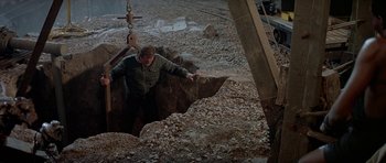 Movie still from “A View to a Kill” (1985), directed by John Glen – A man standing in the middle of a pit of rocks; Wide shot, High angle